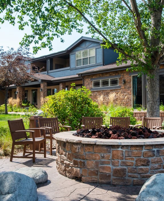 a patio with chairs and a fire pit in front of a house