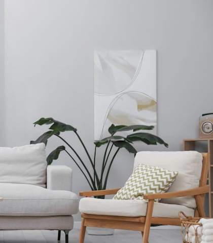 A living room with a white couch, a wooden chair, a wooden table, and a potted plant.