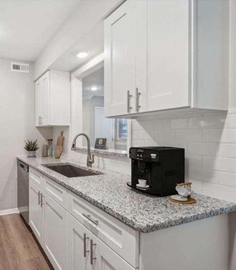 a kitchen with white cabinets and granite counter tops and a stainless steel refrigerator at Lake Johnson Mews Apartments, PRG Real Estate Management, Raleigh, 27606