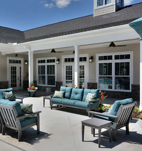 A pool surrounded by chairs and a fire pit.