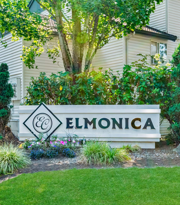 Elmonica Court apartments monument sign with a building and trees in the background