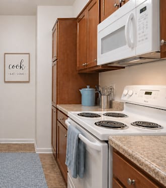 A kitchen with a white stove and wooden cabinets at Louisville Apartments, Louisville..
