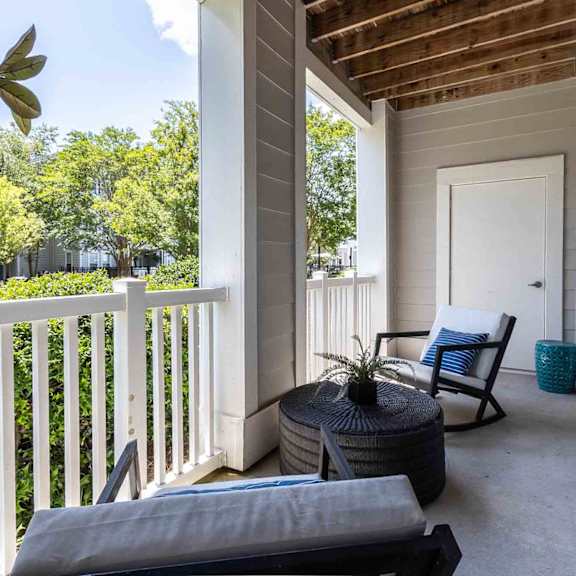 A patio with a white chair and a black ottoman.