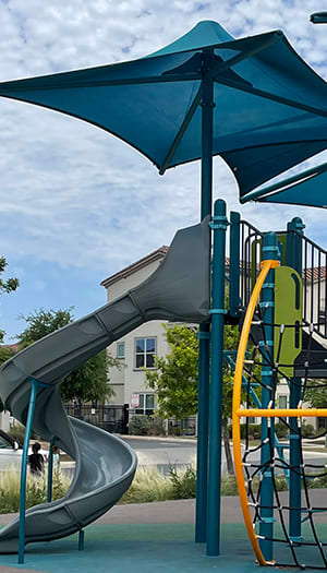 a playground with a slide and umbrella at East Meadows Apartments