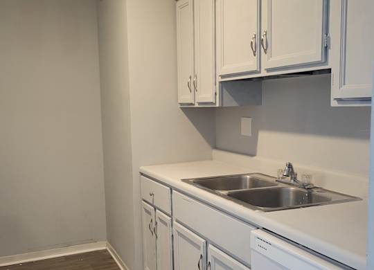 A kitchen with white cabinets and a white wall.
