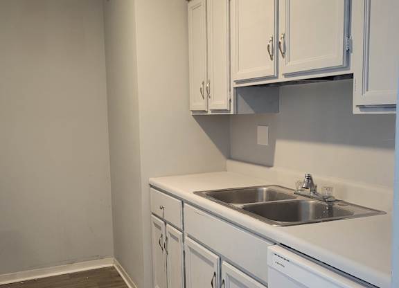 A kitchen with white cabinets and a white wall.