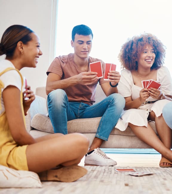 a group of young people sitting on a couch playing cards