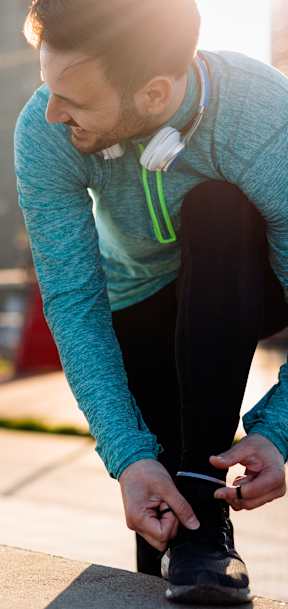 A man and a woman are tying their shoelaces outdoors.