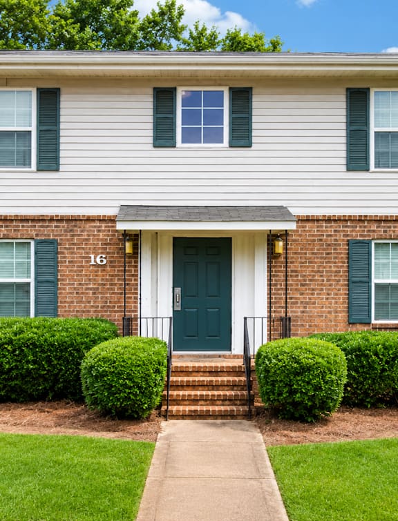 A house with a green door and two windows with green shutters.