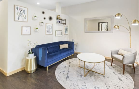 a living room with white walls and a blue couch at Guinevere Apartment Homes, Seattle, WA