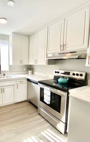 a white kitchen with stainless steel appliances and white cabinets at The Flats on Addison, California, 91423