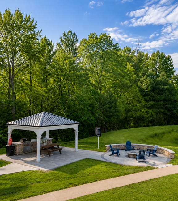 A gazebo is surrounded by a grassy area and trees.