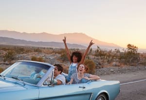 four friends driving in a convertible in the desert