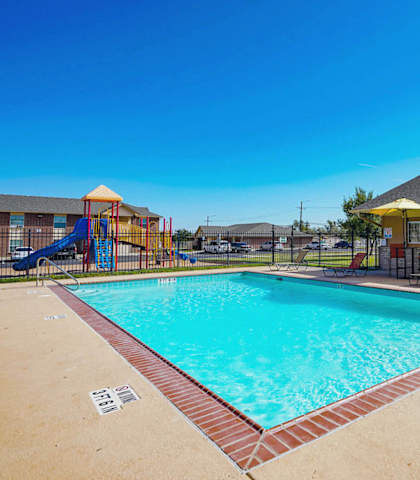 A large outdoor swimming pool with a slide and sun loungers.