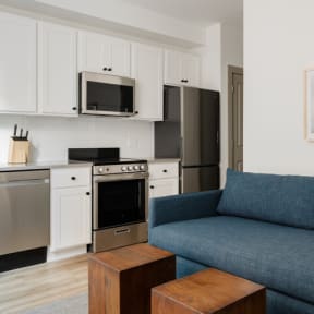 a living room with a blue couch and a kitchen at The Commons On Ludlow Apartments, Philadelphia, PA, 19104