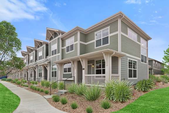 an apartment building with green grass and a sidewalk
