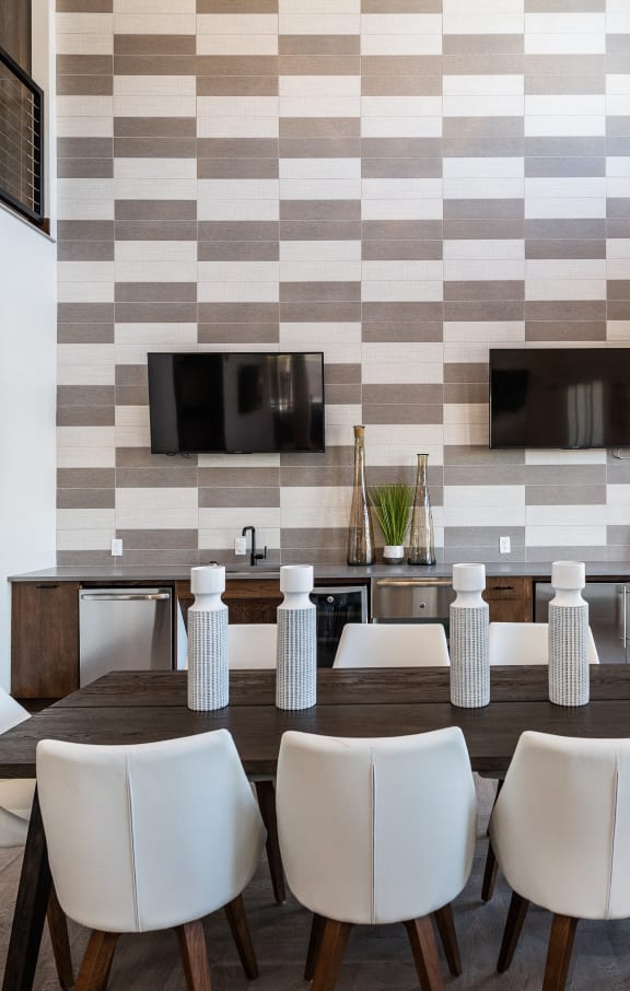 a dining room with a large table and chairs and a wall with two televisions