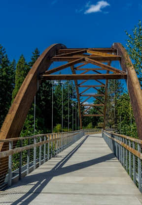 A wooden bridge with metal railings spans across a body of water.