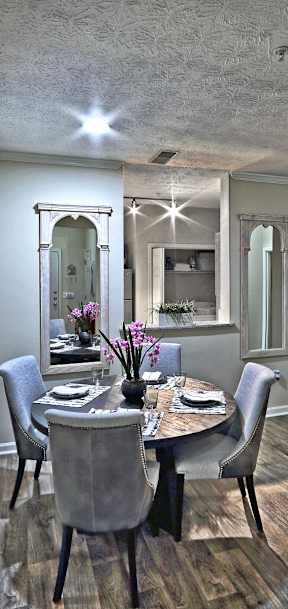 A dining room with a table set for two and a mirror on the wall.