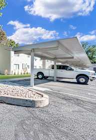 A white car is parked under a white canopy.