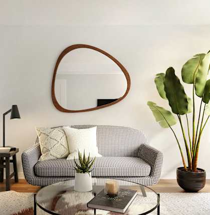 A grey couch with a white pillow and a candle on a coffee table.