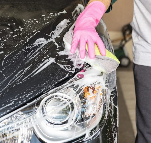 a person is washing the hood of a car with a rag
