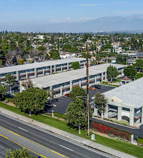 A large building with a grey roof is situated on a street corner. at Canyon Shadows Apartments, Riverside California