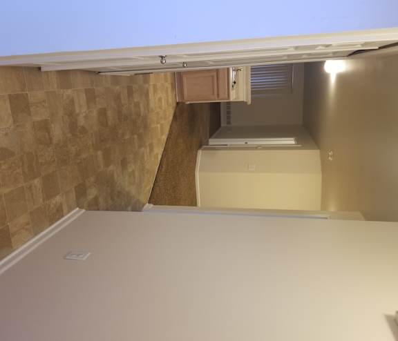 A room with a tiled wall and a window with blinds.