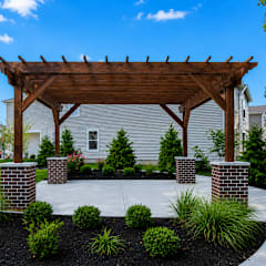 A wooden pergola is over a landscaped area.