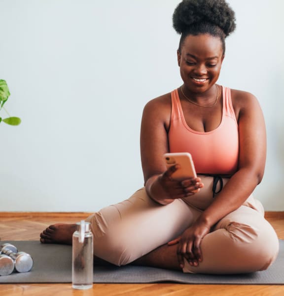 a woman sitting on a yoga mat looking at her phone