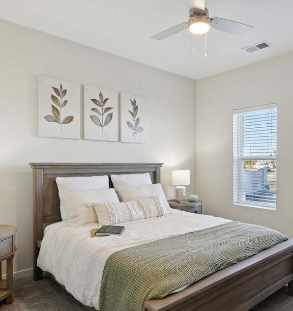 A bedroom with a bed, nightstand, and a ceiling fan.