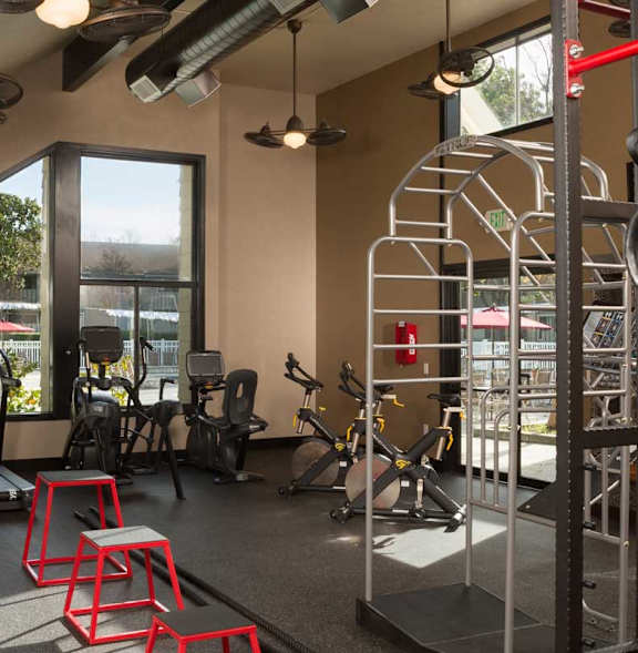 A gym with a variety of equipment including a treadmill, weights, and a pull up bar at The Woods Apartments, California, 95136