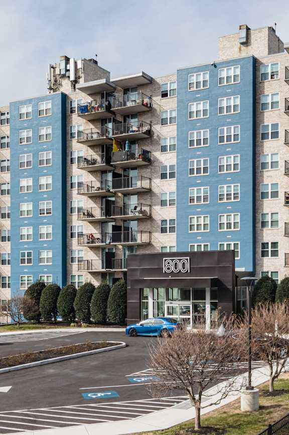 A view of a street with cars and apartment buildings.