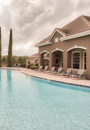 a patio with tables chairs and umbrellas at the whispering winds apartments in pearland,