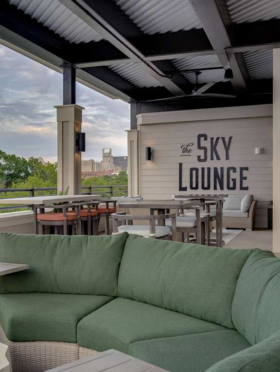 a patio with a green couch and a view of the sky lounge
