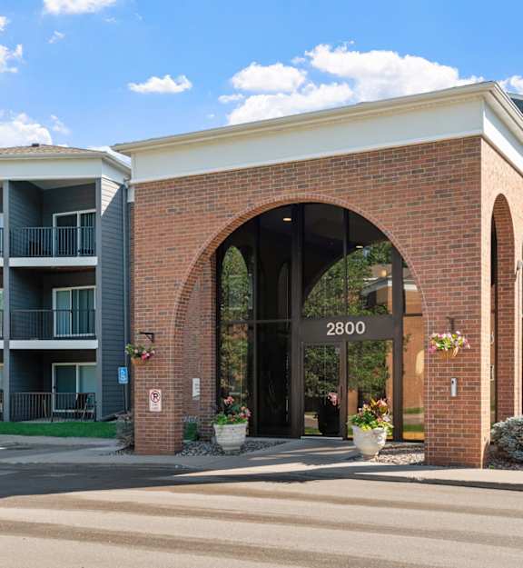 the archway of a brick apartment building with balconies  at Cedars Lakeside, Little Canada, Minnesota