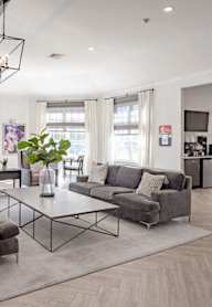 A spacious living room with grey couches and a wooden floor.