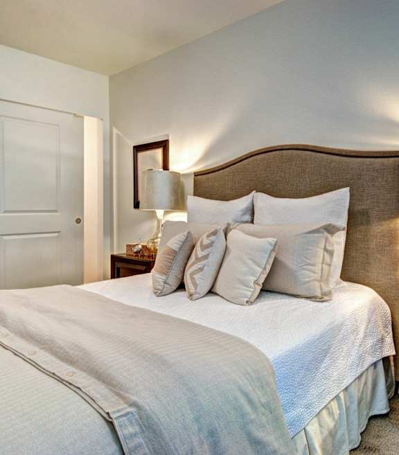 A bedroom with a large bed and a nightstand with a lamp.