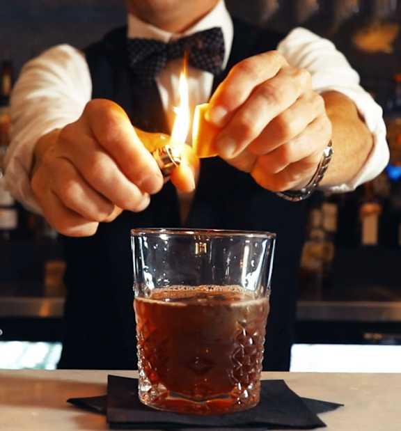 A bartender is making a drink at the bar.