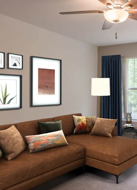 A living room with a brown couch, a ceiling fan, and a window with blue curtains.