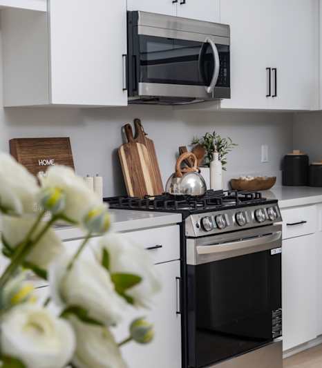 A bouquet of white roses is in the foreground of a modern kitchen.