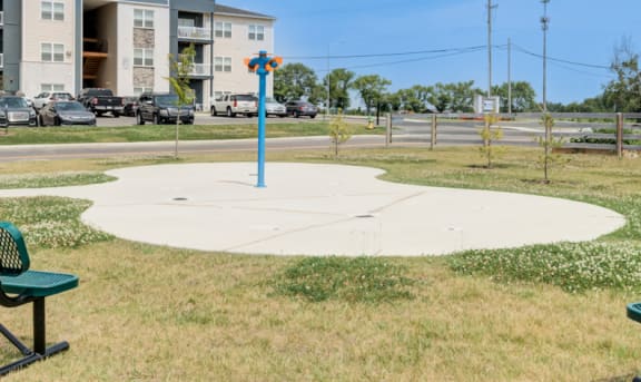 two park benches in a park with a pole and buildings
