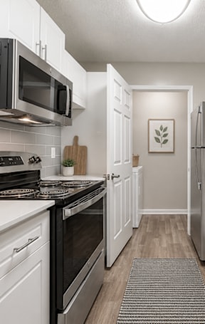 A modern kitchen with black appliances and white cabinets.