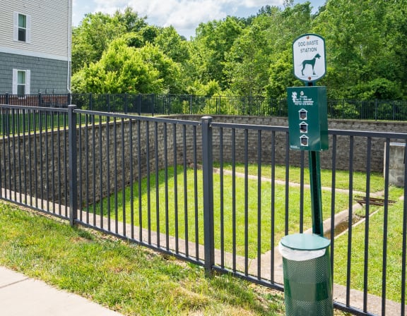 a black wrought iron fence with a green sign on it and a yard behind it