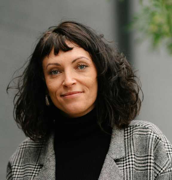 A woman with a black turtleneck and a plaid jacket.