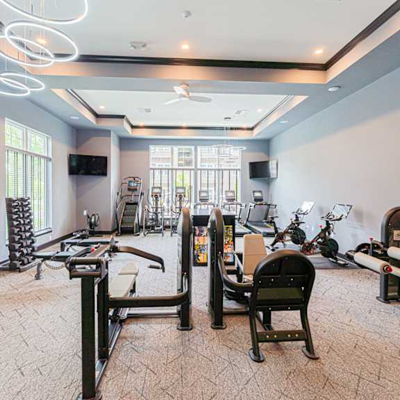 A spacious gym with various exercise equipment and mirrors.