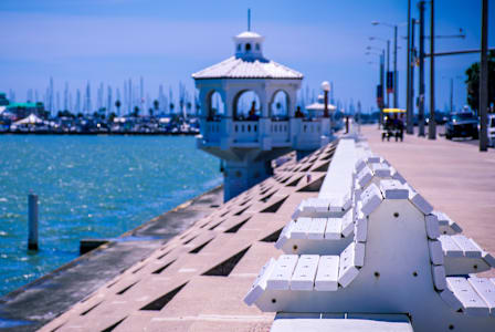 A white gazebo is situated on a pier next to a body of water.