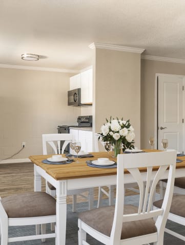 a dining room with a table and chairs and a kitchen in the background  at North Washington Apartments