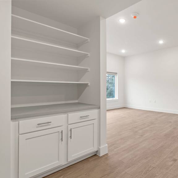 A white room with wooden floors and a staircase on the left side.