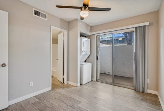 A room with a ceiling fan and a window with a view of a parking lot.